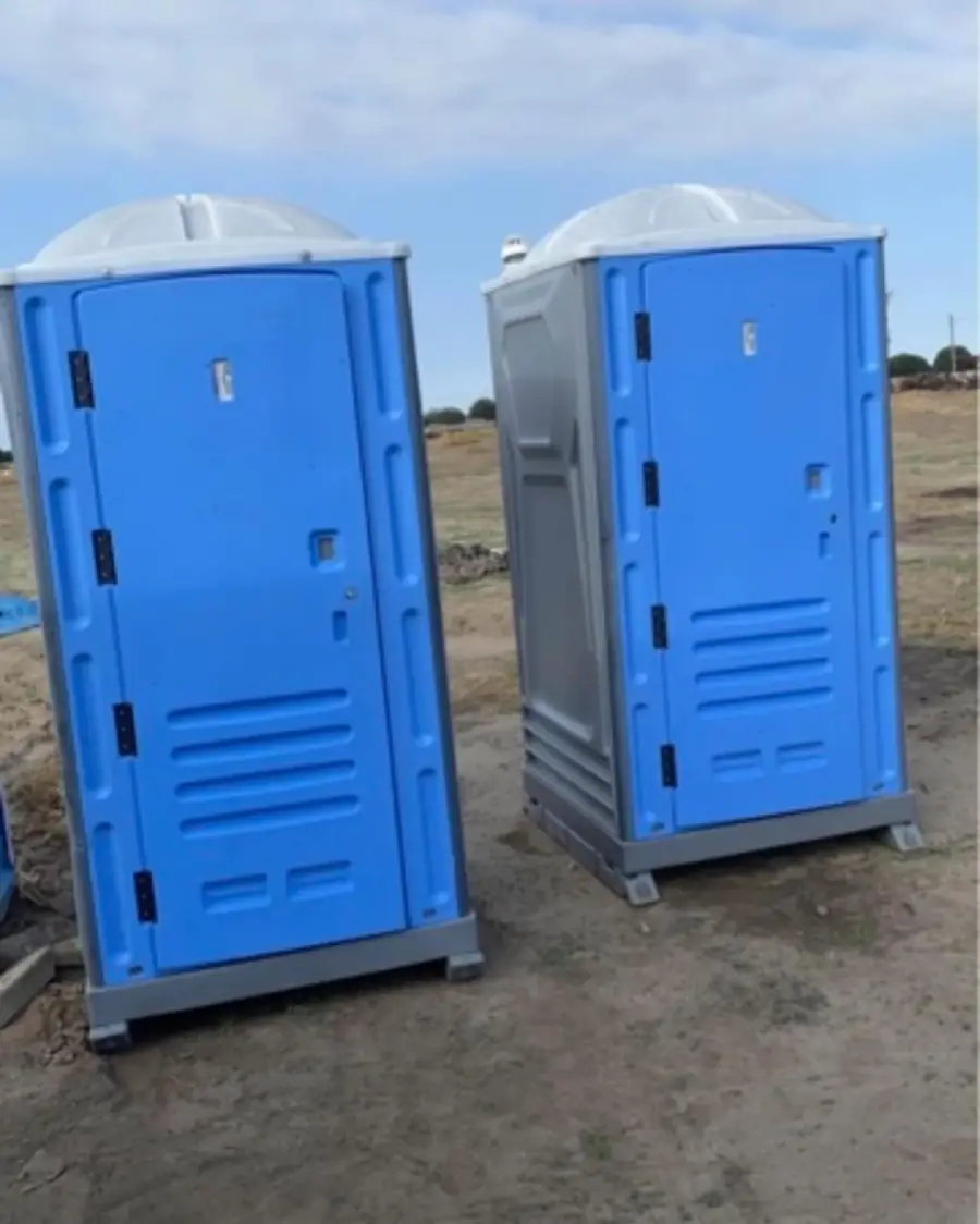 Two portable toilets on an open job site where spring wind is strongest
