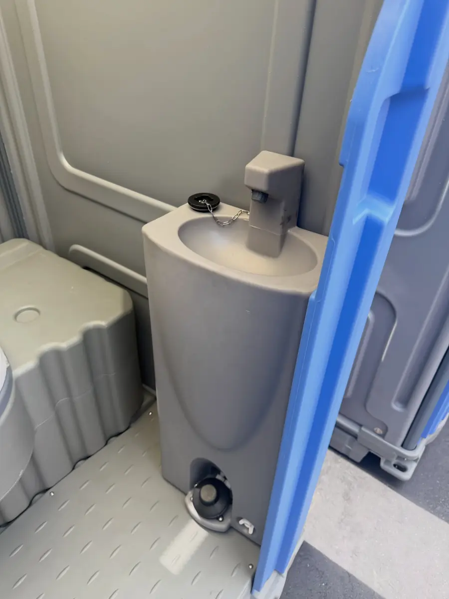 Foot-pump sink and soap dispenser inside a deluxe portable toilet