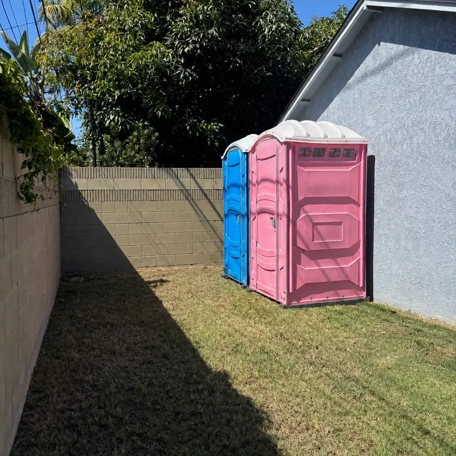 Two portable toilets in a side yard ready for a game-day party